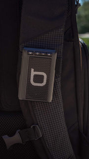 Black Bumpboxx Bluetooth Retro Pager Beeper clipped on backpack. 