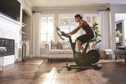 Female athlete uses Echelon Smart Connect Bike EX5 in living room. 