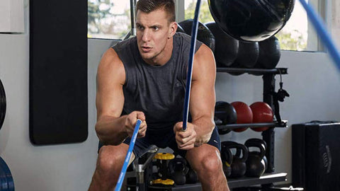 Rob Gronkowski using blue Gronk Fitness Inertia Wave during workout in gym setting. 