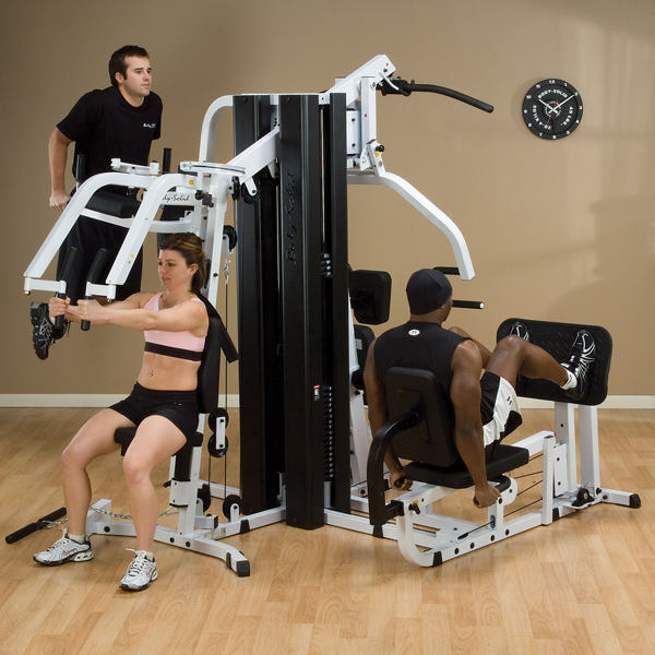 Two male athletes and a female athlete use Body-Solid EXM3000LPS Gym System for dips, leg press and chest flies at same time. 